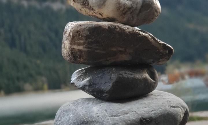 Gestapelte Steine vor einem Bergsee – kleine Schritte, große Wirkung
