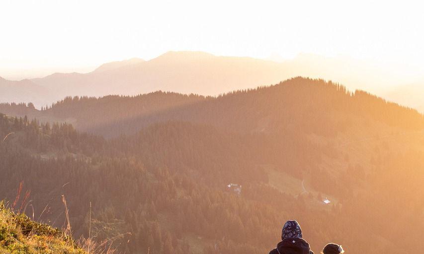 Zwei Wanderer gehen bei Sonnenaufgang einen Hügel hinauf