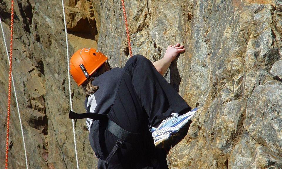 Kletterer mit orangem Helm in einer Felswand