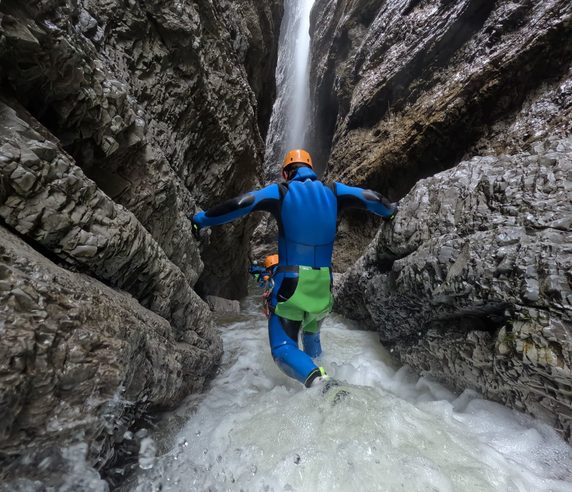Teilnehmer steigt durch einen Wasserfall in der Strubklamm ab